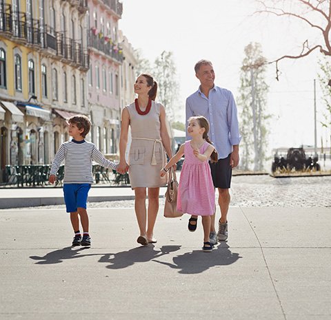 A family walking through a colorful European port city, enjoying a sunny day | MSC Cruises