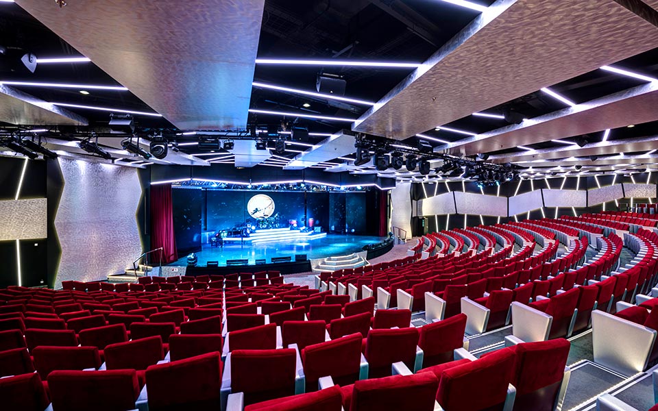 A modern theater with red seats and a stage on an MSC cruise ship | MSC Cruises