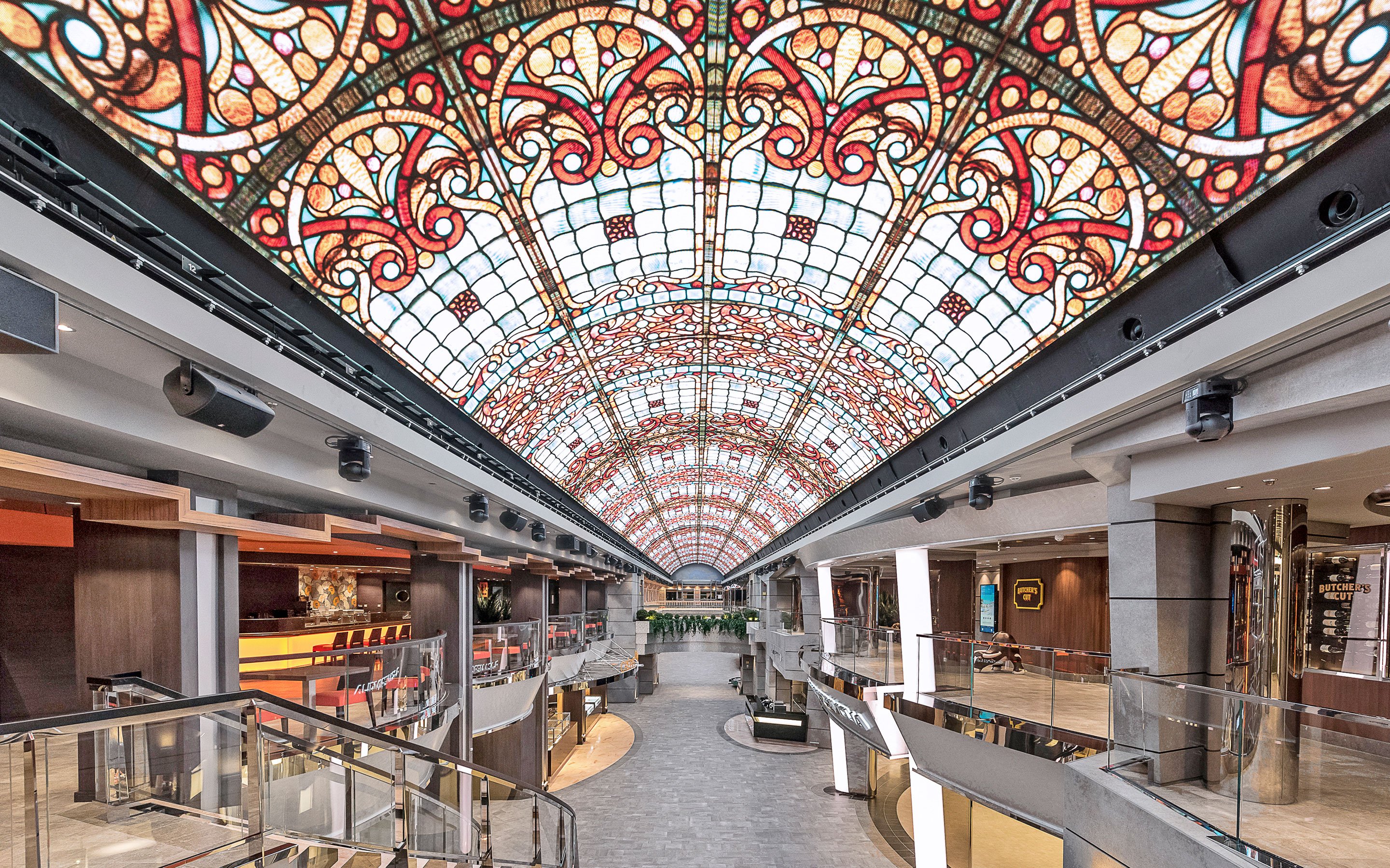 Luxurious cruise ship promenade with vibrant stained-glass ceiling and upscale shops | MSC Cruises Luxurious cruise ship promenade with vibrant stained-glass ceiling and upscale shops | MSC Cruises